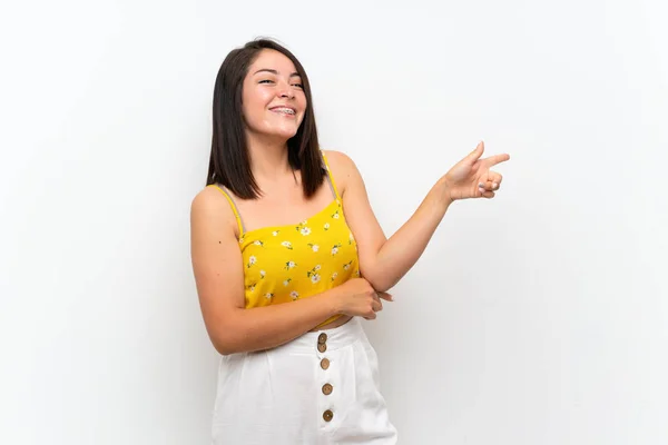 Young Mexican woman over isolated wall pointing finger to the side