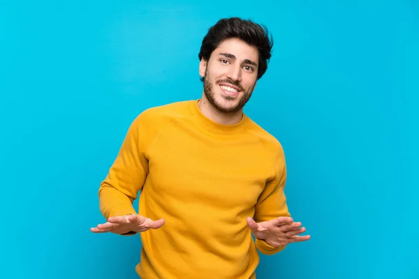 Handsome over isolated blue wall smiling