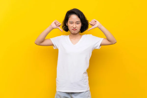 Asiática Joven Mujer Sobre Aislado Amarillo Pared Mostrando Pulgar Abajo —  Fotos de Stock