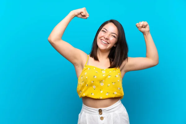 勝利を祝う孤立した青い背景の上に若いメキシコの女性 — ストック写真