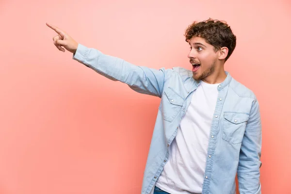 Hombre Rubio Sobre Pared Rosa Señalando Hacia Fuera —  Fotos de Stock