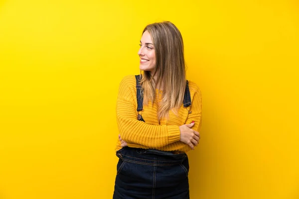 Vrouw Met Overalls Geïsoleerde Gele Muur Lachend — Stockfoto