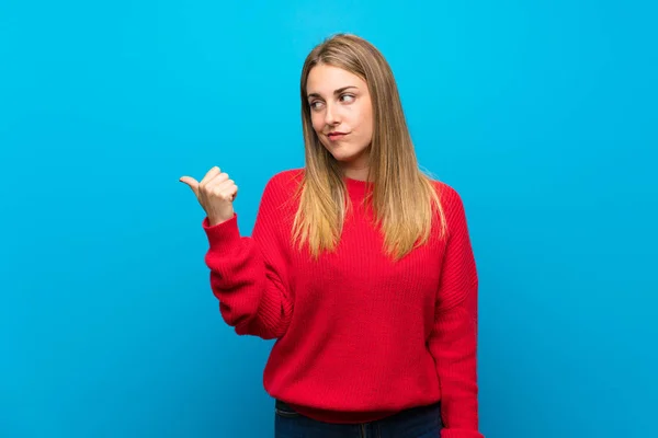 Vrouw Met Rode Trui Blauwe Muur Ongelukkig Wijzend Naar Zijkant — Stockfoto