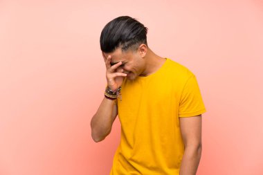 Izole pembe duvar üzerinde sarı gömlekli genç adam gülüyor