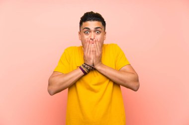 Sürpriz yüz ifadesi ile izole pembe duvar üzerinde sarı gömlekli genç adam