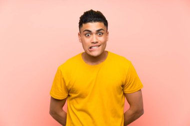 Izole pembe duvar üzerinde sarı gömlek li genç adam şüpheleri olan ve yüz ifadesi karıştırmayın