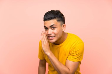 Young man with yellow shirt over isolated pink wall whispering something