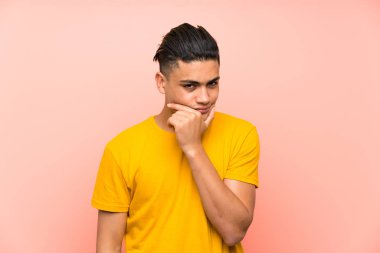 Izole pembe duvar üzerinde sarı gömlekli genç adam bir fikir düşünme