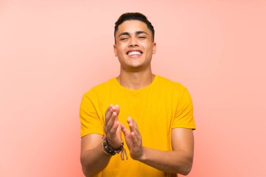 Young man with yellow shirt over isolated pink wall applauding