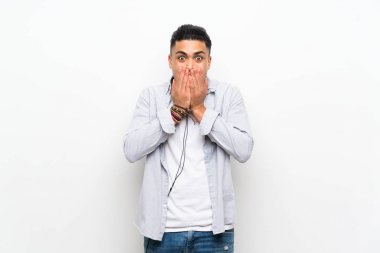 Sürpriz yüz ifadesi ile kulaklık ile izole beyaz duvar üzerinde genç adam