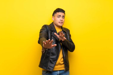 Young man over isolated yellow background nervous stretching hands to the front