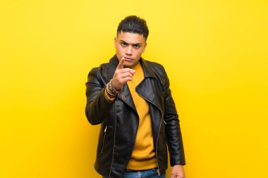 Young man over isolated yellow background frustrated and pointing to the front