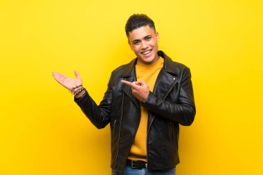 Bir reklam eklemek için avuç üzerinde copyspace hayali tutan izole sarı arka plan üzerinde genç adam