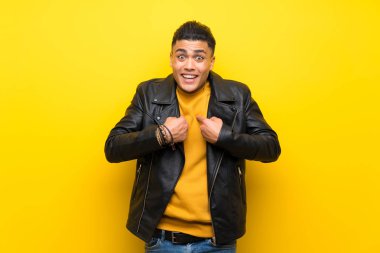 Young man over isolated yellow background with surprise facial expression