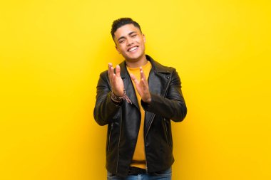 Young man over isolated yellow background applauding after presentation in a conference