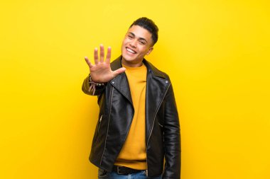 Young man over isolated yellow background counting five with fingers