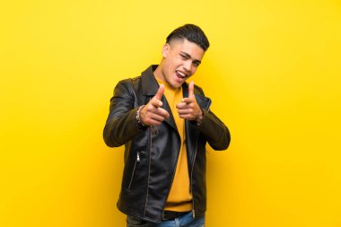 Young man over isolated yellow background pointing to the front and smiling