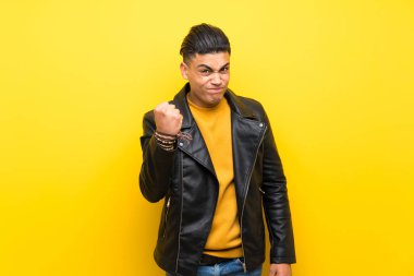 Young man over isolated yellow background with angry gesture