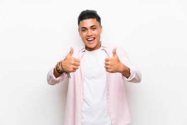 Izole beyaz duvar üzerinde genç adam jest kadar bir başparmak veren