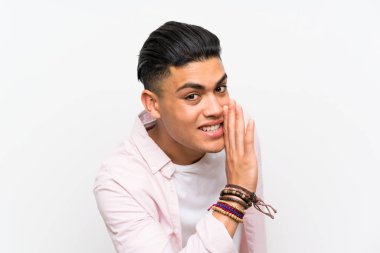 Young man over isolated white wall whispering something