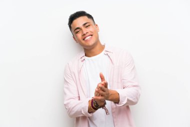 Young man over isolated white wall applauding
