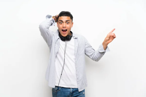 Junger Mann Über Isolierte Weiße Wand Mit Kopfhörern Überrascht Und — Stockfoto