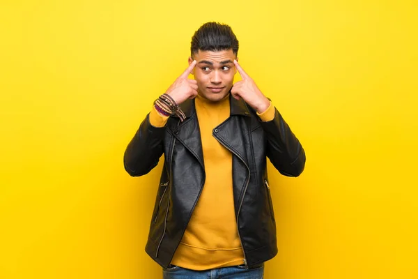 Young man over isolated yellow background having doubts and thinking