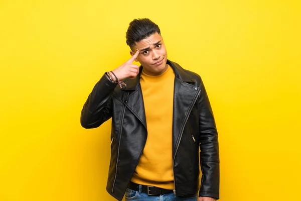 Young man over isolated yellow background making the gesture of madness putting finger on the head