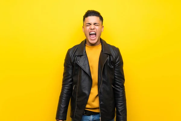 Young man over isolated yellow background shouting to the front with mouth wide open