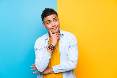 Izole renkli arka plan üzerinde genç adam bir fikir düşünme