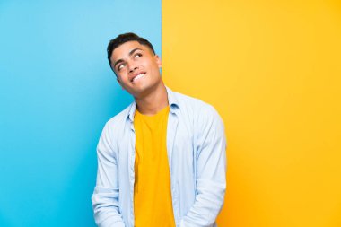 Young man over isolated colorful background laughing and looking up