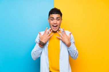 Sürpriz yüz ifadesi ile izole renkli arka plan üzerinde genç adam
