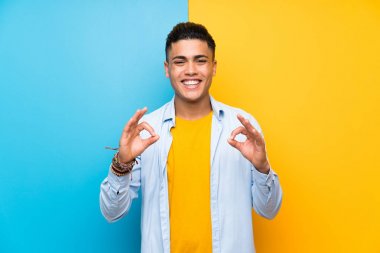Parmakları ile ok işareti gösteren izole renkli arka plan üzerinde genç adam