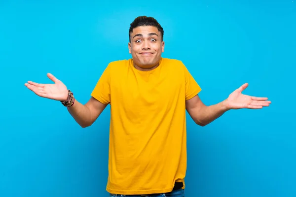 Jovem Com Camisa Amarela Sobre Fundo Azul Isolado Com Dúvidas — Fotografia de Stock