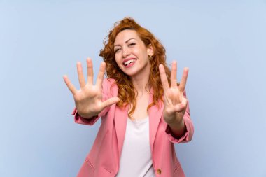 İzole mavi duvar üzerinde takım elbiseli Redhead kadın parmakları ile sekiz sayma