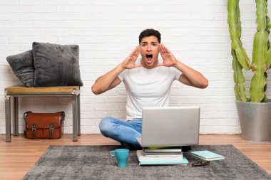 Yakışıklı adam ağzı tamamen açık bağırarak dizüstü bilgisayarı ile katta oturan