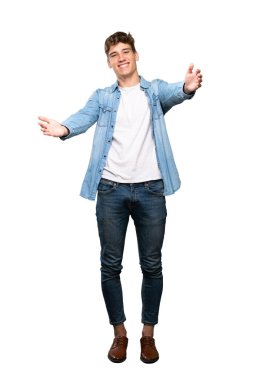 Yakışıklı bir genç adam sunan ve izole beyaz arka plan üzerinde el ile gelmek için davet tam uzunlukta bir çekim