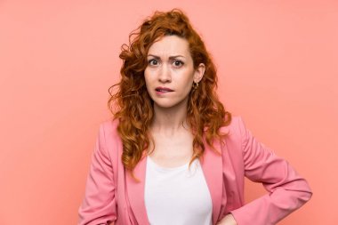 Izole pembe duvar üzerinde takım elbiseredhead kadın şüpheleri olan ve yüz ifadesi karıştırmayın
