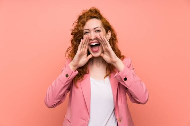Izole pembe duvar üzerinde takım elbiseredhead kadın ağzı tamamen açık bağırarak