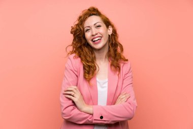 Izole pembe duvar gülerek üzerinde takım elbiseli Redhead kadın