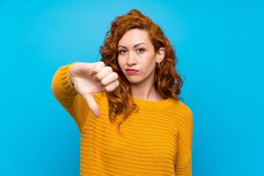 Sarı kazak ile Redhead kadın olumsuz ifade ile başparmak aşağı gösteren