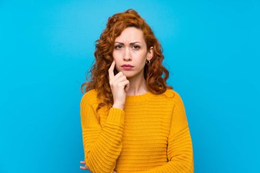 Sarı kazak lı kızıl saçlı kadın ön plana bakıyor