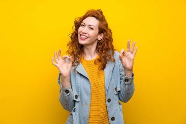 Izole sarı arka plan üzerinde Redhead kadın parmakları ile ok işareti gösteren