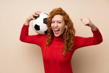 Bir futbol topu tutan balıkçı yaka kazak ile Redhead kadın