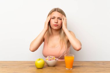 Genç sarışın kadın kahvaltı mutsuz ve bir şey ile sinirli yaşıyor. Negatif yüz ifadesi