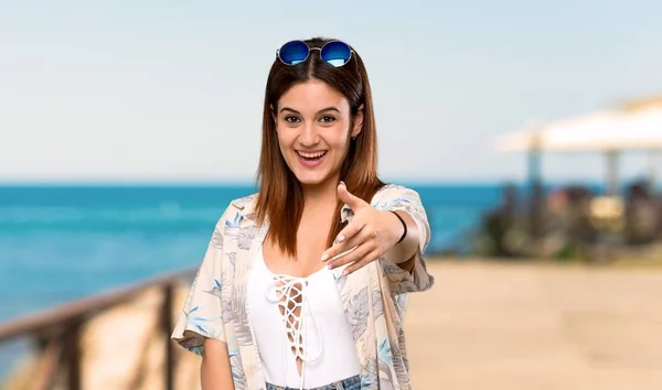 Young woman in bikini in summer holidays shaking hands for closing a good deal at the beach