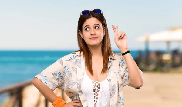 Young woman in bikini in summer holidays with fingers crossing and wishing the best at the beach