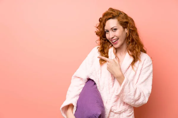 Redhead woman in dressing gown pointing finger to the side