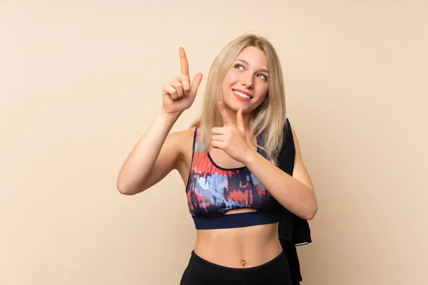 Jonge Blonde Sportvrouw Geïsoleerde Muur Wijzend Met Wijsvinger Een Geweldig — Stockfoto