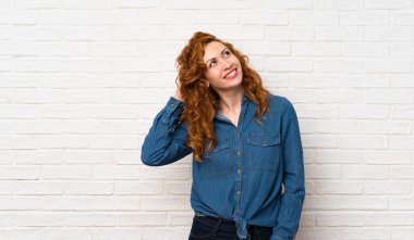 Beyaz tuğla duvar üzerinde Redhead kadın bir fikir düşünme